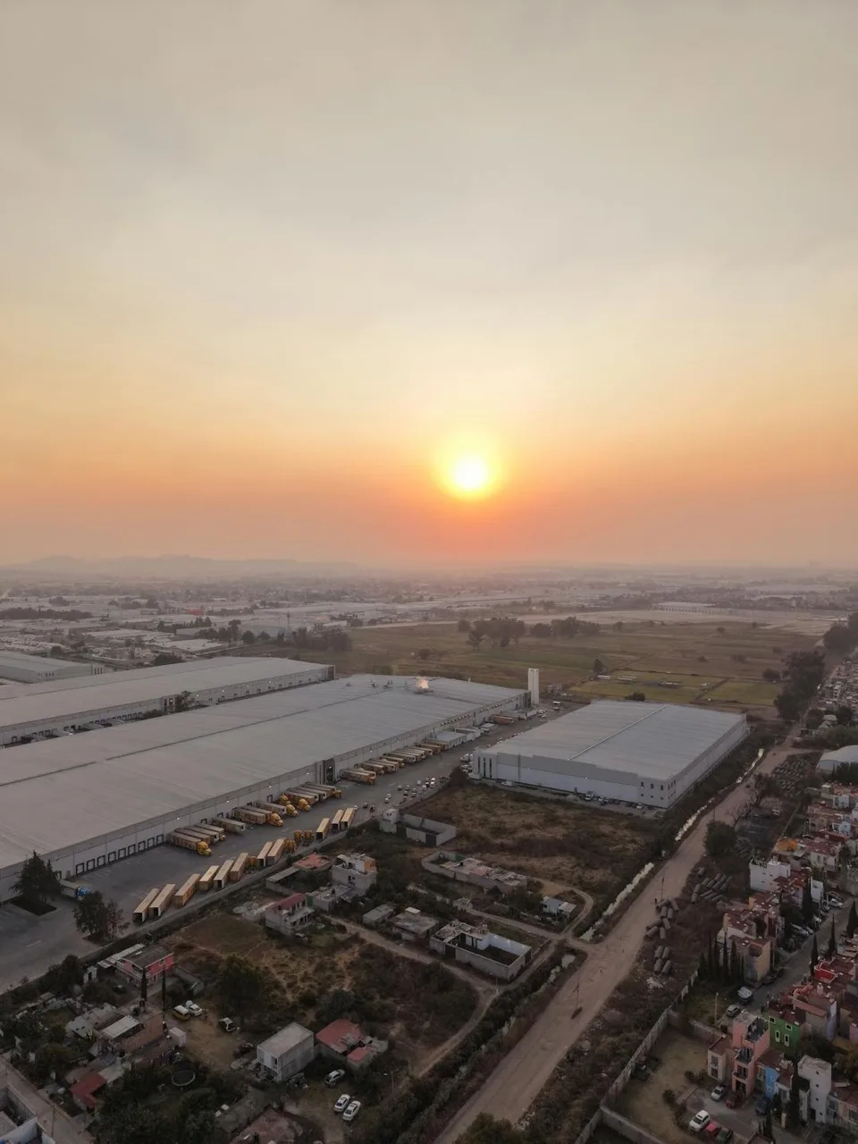 Aerial industrial edge at sunrise, suggesting scale, throughput, and system exposure at the urban perimeter.