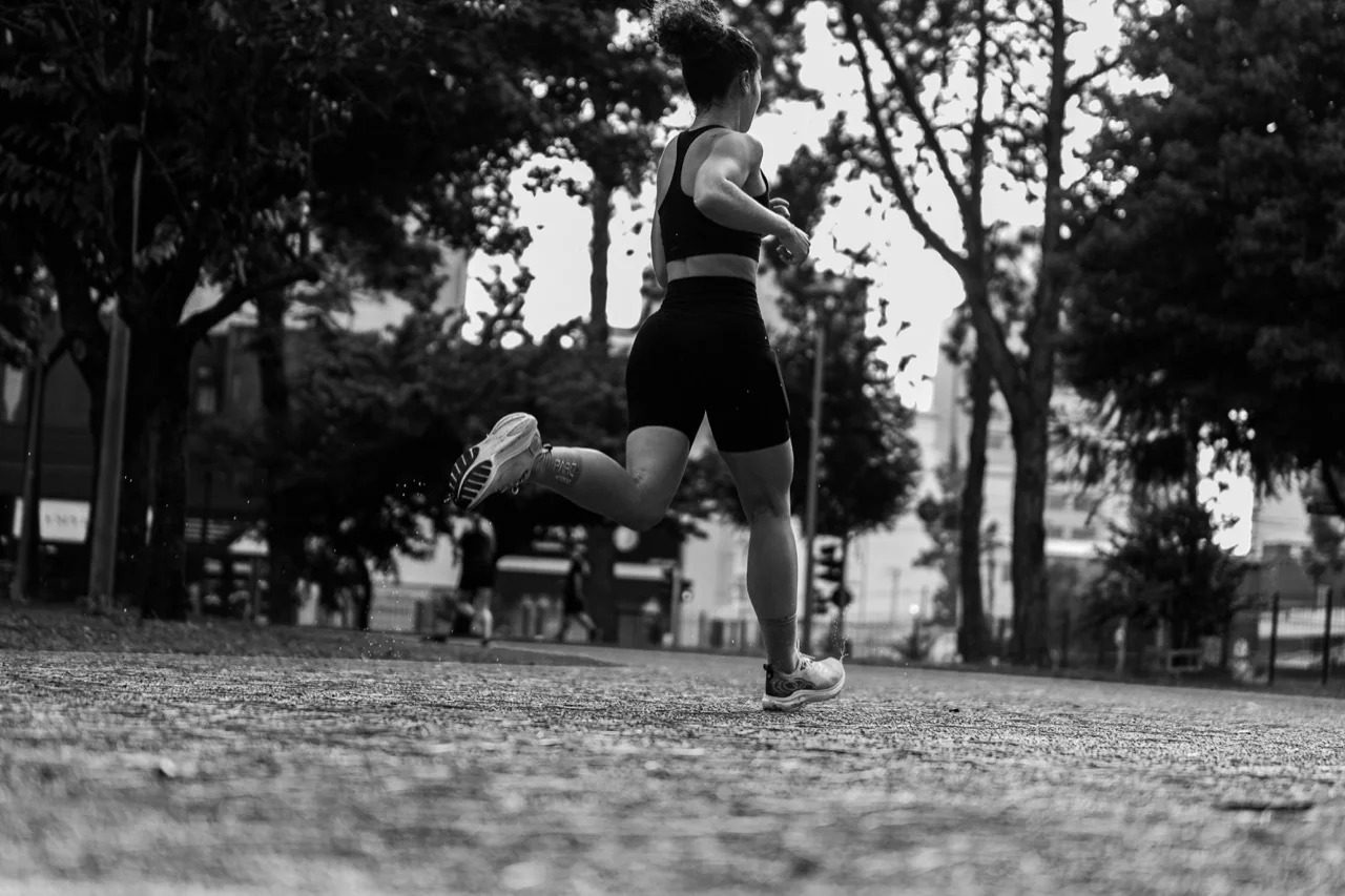 Black-and-white urban running scene from behind, signaling performance, movement, and consumer credibility without relying on a cropped portrait.