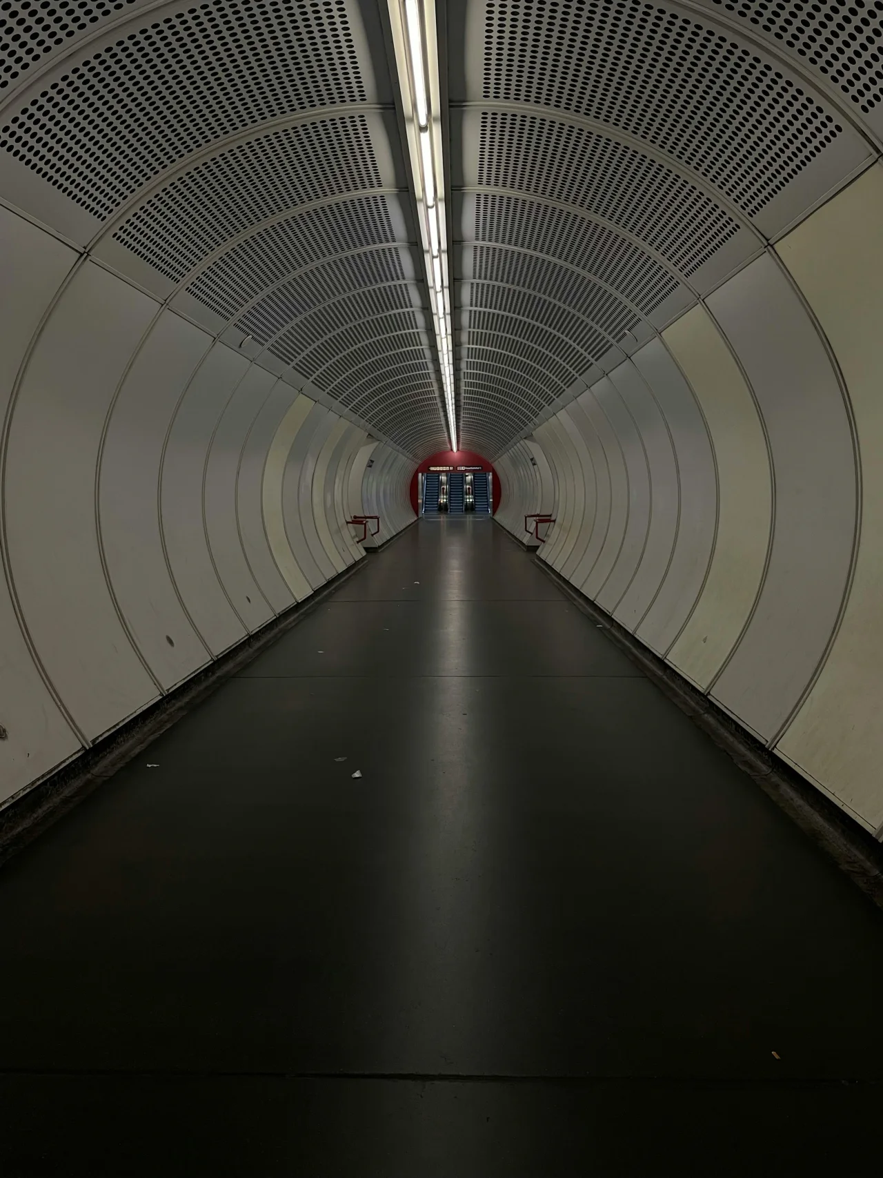 Symmetrical white tunnel receding to a vanishing point, signaling disciplined passage, geometry, and constrained direction.
